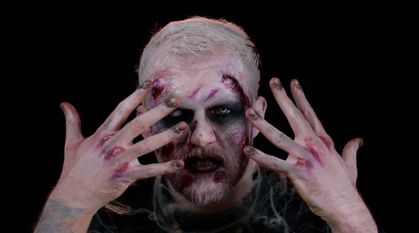 Asustadizo herido zombie muertos vivientes haciendo caras, mira a la cámara oculta a través de las manos sonríe terriblemente — Foto de Stock