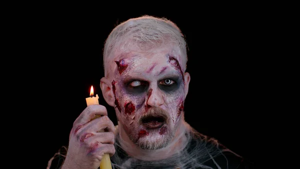 Man alleen met Halloween zombie bloederige gewonde make-up, proberen te schrikken betovert bezweringen over een kaars — Stockfoto