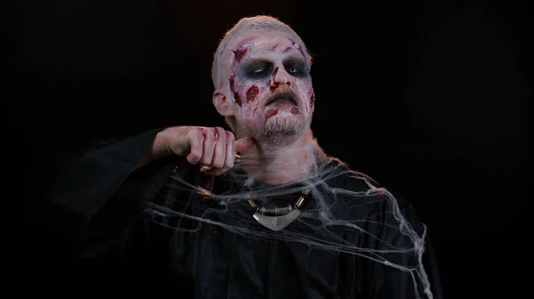 Baljós ember Halloween zombi próbál ijeszteni mutató gyilkos gesztus, fut egy ujj végig a nyakán — Stock Fotó