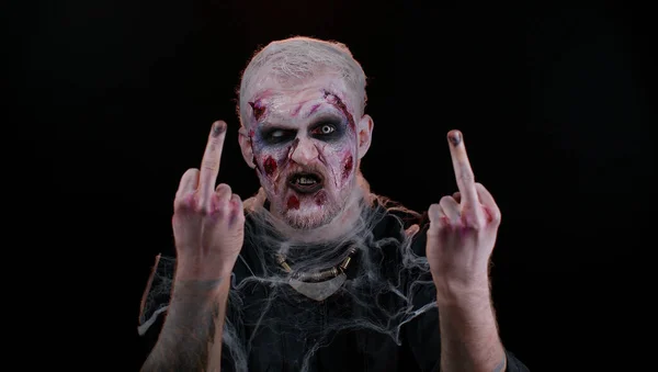 Hombre zombi agresivo de Halloween mostrando alrededor de los dedos medios, demostrando gesto grosero protesta — Foto de Stock