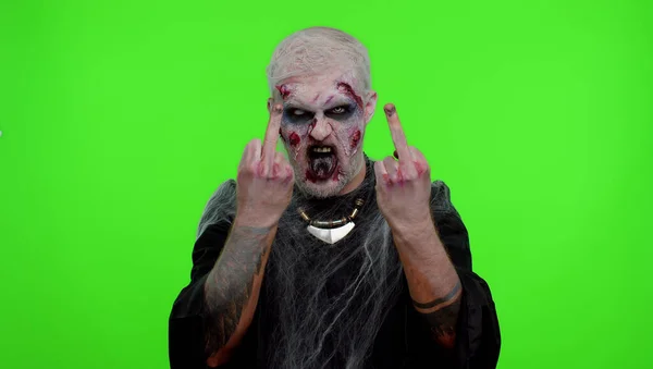 Aggressive Halloween zombie man showing around middle fingers, demonstrating protest rude gesture