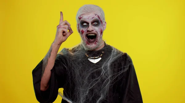 Inspirierter Halloween-verrückter Zombie-Mann zeigt mit offenem Mund den Finger nach oben und zeigt Eureka-Geste — Stockfoto