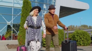 Yaşlı koca emekli oldu, turistler havaalanı terminaline tekerlekli bavullarıyla gitmek için gidiyorlar.