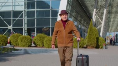Emekli kıdemli turist büyükbaba işadamı havaalanı kapısından bavul çantasıyla geliyor.