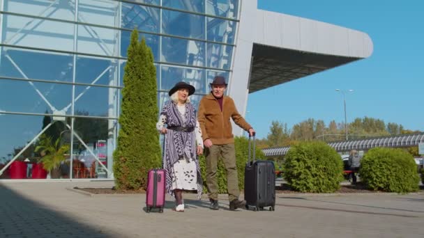 Старший пенсионер туристов бабушка дедушка пешком из аэропорта зал с багажом на колесах — стоковое видео