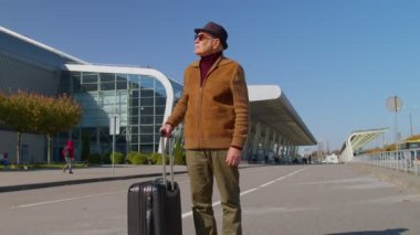 Emekli büyükanne iş kadını valiziyle havaalanı binasına, tren istasyonuna yürüyor.