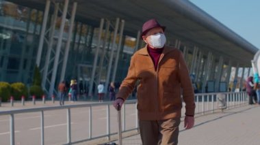 Yaşlı turist büyükbaba Koruyucu Yüz Maskesi takıyor, havaalanı yakınlarında koronavirüsten kaçının.
