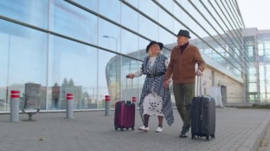 Kıdemli emekli turist büyükanne büyükbaba havaalanından tekerlekli bavulla geliyor.