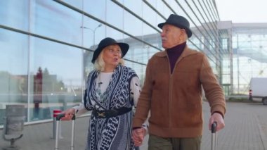 Yaşlı koca emekli oldu, turistler havaalanı terminaline tekerlekli bavullarıyla gitmek için gidiyorlar.