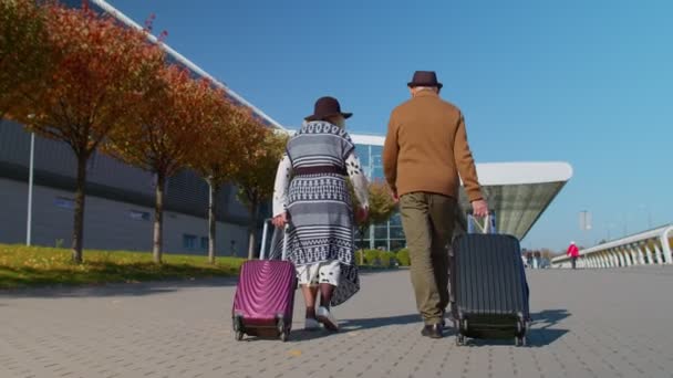 Senior pensionär turister mormor farfar promenader till flygplatsen hall med bagage på hjul — Stockvideo