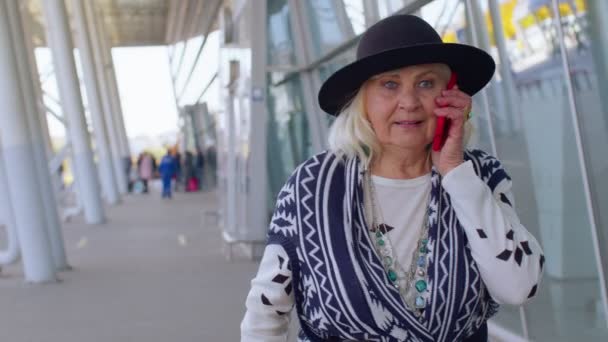 高级旅游祖母在国际机场大厅里散步，用手机，说话 — 图库视频影像