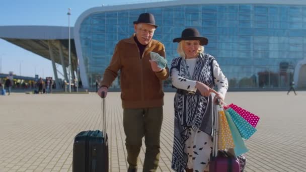 Senior rik pensionär turister promenader med shoppingväskor från semester innehav dollar pengar kontanter — Stockvideo