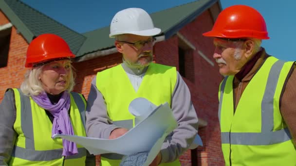 Architekt se staršími stavebními inženýry diskutuje o projektové práci s plánem výstavby nového domu — Stock video