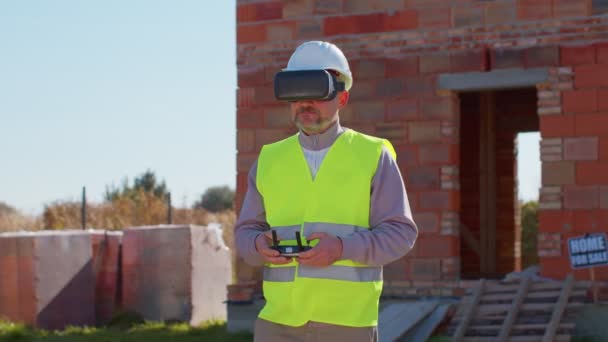 Construtor profissional drone operador em capacete realidade virtual em pé na frente do canteiro de obras — Vídeo de Stock