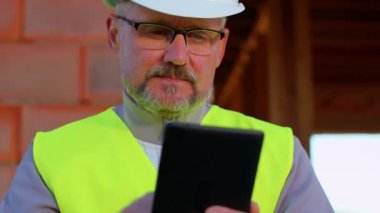 İnşaat mühendisi mimar inşaat sahasında çalışmayı kontrol etmek için dijital tabletle çalışıyor