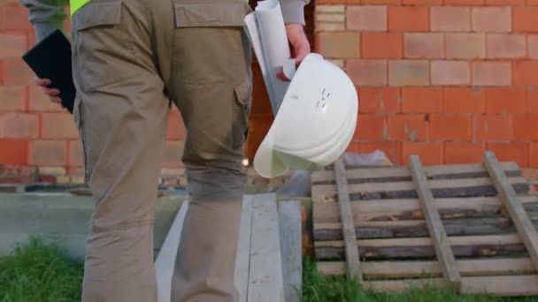 Архітектор проекту будівництва з шоломом, що йде на будівельний майданчик — стокове відео