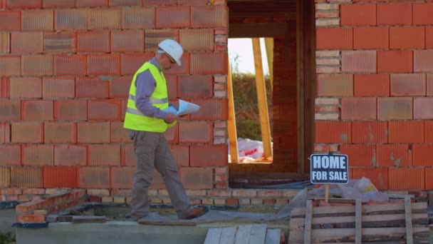 Рабочий проектировщик-архитектор анализирует чертежи на строительной площадке дома, недвижимости — стоковое видео