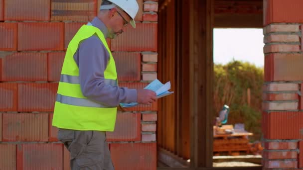 Engenheiro civil arquiteto especialista analisando plantas para controlar o trabalho no canteiro de obras — Vídeo de Stock