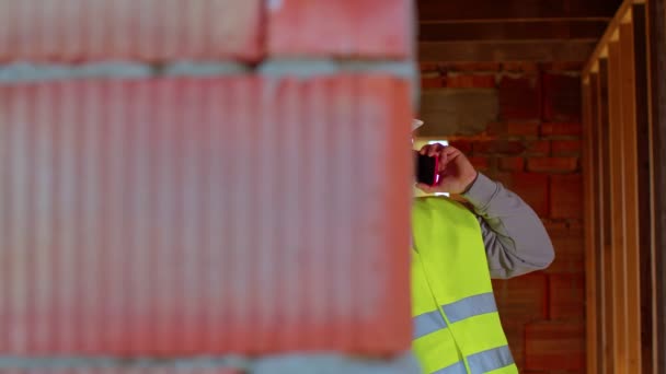 Professionele bouwkundige architect in gesprek op mobiele telefoon om werken op de bouwplaats te controleren — Stockvideo