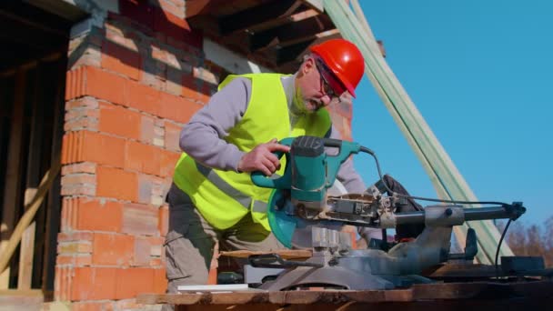 Snickare man med cirkulär elektrisk såg för att skära träskivor, träarbetare på byggarbetsplatsen — Stockvideo