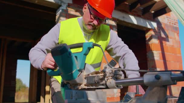 Carpenter man using circular electric saw for cutting wooden boards, woodworker at construction site — Stock Video