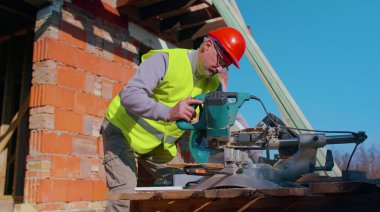 Marangoz tahta kesmek için elektrikli testere kullanıyor. İnşaat alanında ahşap işçisi.