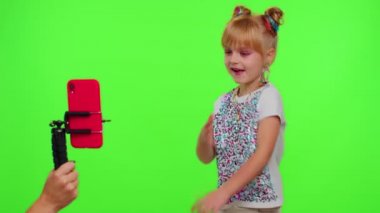 Neşeli, komik, küçük kız çocuk kameranın önünde dans ediyor. Krom anahtar duvarında telefon kullanarak video çekiyor.