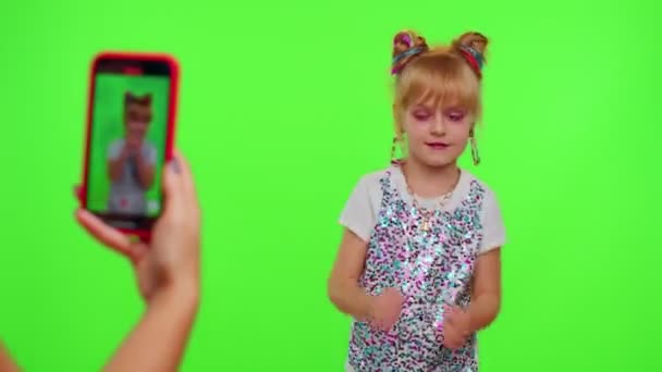 Vrolijk grappig klein tiener meisje kind dansen op camera filmen video met behulp van telefoon op chroma key wall — Stockvideo