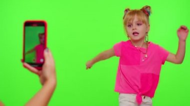 Mutlu funky blogger çocuk kız, sosyal ağ için akıllı telefondan komik dans videoları kaydediyor.
