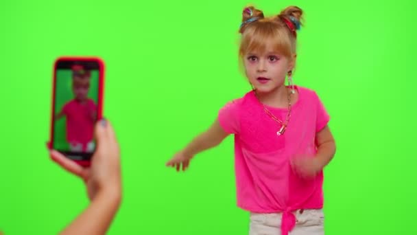 Happy little kid girl blogger vor der Handykamera aufzeichnen video genießen dance content on chroma key — Stockvideo