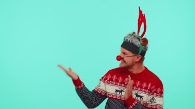 Kırmızı kazaklı adam Noel Baba. Başparmağını kaldırıp boş yeri işaret ediyor. Reklam alanı.