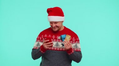 Kırmızı kazaklı adam cep telefonu, plastik banka kartı, kazan, kalebrat kullan.