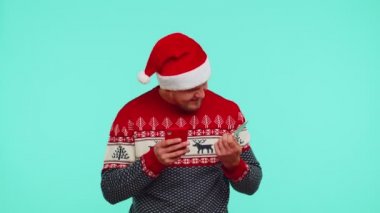 Kırmızı kazaklı adam cep telefonu ve plastik banka kartı kullanıyor. Kazan, kazan, vay canına.
