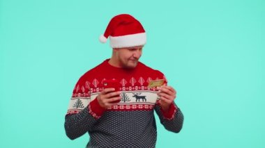 Noel kazaklı bir adam kredi kartı, akıllı telefon kullanarak internetten para alışverişi yapıyor.
