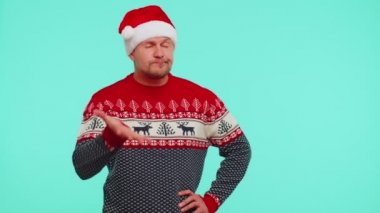 Noel kırmızı kazaklı üzgün bir adam avuç içi hareketi yapıyor, canı sıkkın, hayal kırıklığına uğramış, kötü sonuç almış.