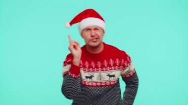 Noel kazağı giymiş hoşnutsuzca el kol hareketi yapan, başarısızlıktan dolayı azarlayan hoşnutsuz bir adam.