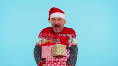 Kırmızı kazaklı adam, Noel Baba şapkalı, gülümseyen, elinde bir sürü hediye kutusu olan yeni yıl hediyesi alışverişi yapan.