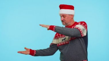 Kırmızı kazaklı adam Noel Baba. Başparmağını kaldırıp boş yeri işaret ediyor. Reklam alanı.