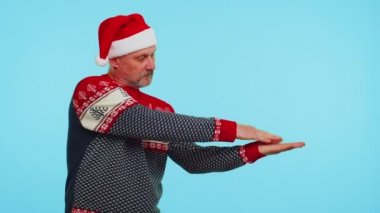 Adam kırmızı Noel geyiği süveteri giyiyor ve boş reklam alanına işaret ediyor.