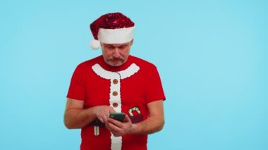 Şık bir Noel tişörtü giyen, akıllı telefon görünümlü, neşeli bir adam. Başarılı olma şansı.