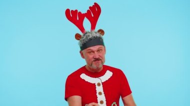 Noel tişörtlü hoşnutsuz bir adam hoşnutsuzlukla el hareketi yapıyor, başarısızlıktan dolayı azarlıyor.