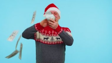 Noel kırmızı kazak ve şapkalı zengin adam harcamayı gösteriyor, etrafa para saçıyor, alışveriş yapıyor.