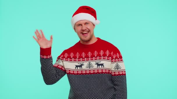 Uomo in maglione rosso Natale onde mano palmo nel gesto ciao accoglie qualcuno per festeggiare il nuovo anno — Video Stock