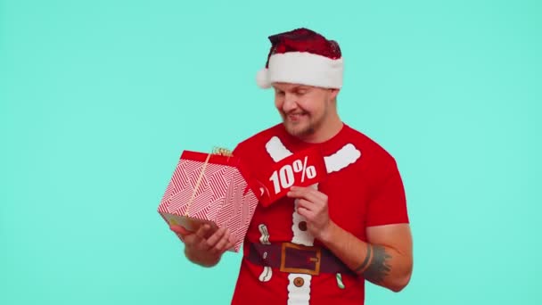 Man in red Christmas t-shirt δείχνει κουτί δώρου και 10 τοις εκατό έκπτωση επιγραφές banner σημείωμα κειμένου — Αρχείο Βίντεο