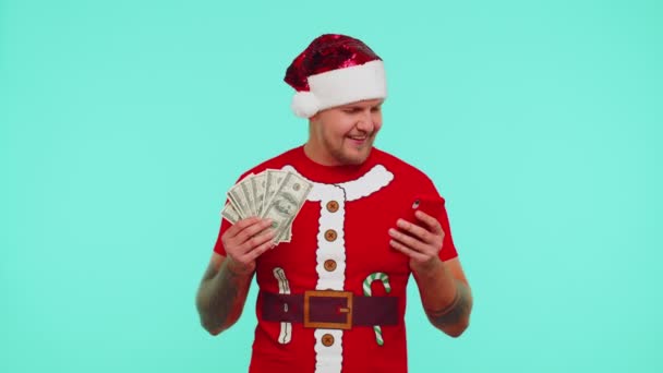 Man in Kerst t-shirt op zoek smartphone oprecht verheugen win succes geluk met het ontvangen van geld — Stockvideo