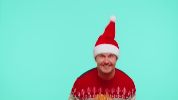 Fröhlicher Mann im Weihnachtsmann-Pullover präsentiert eine Weihnachtsgeschenkbox, streckt die Hände in die Kamera — Stockvideo
