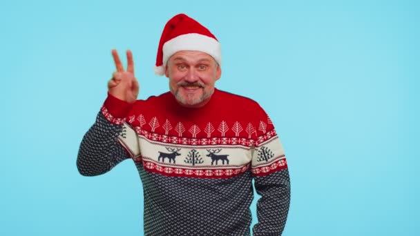 Позитивный мужчина в рождественском свитере с оленями волнами ладонь в привет жест приветствует кого-то — стоковое видео