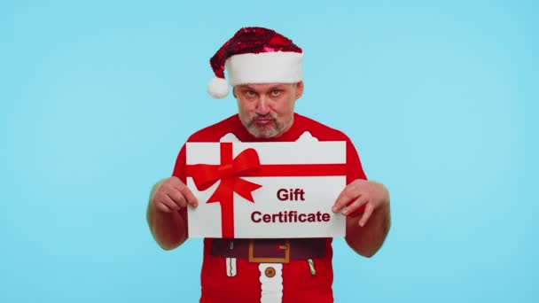 El hombre divertido lleva camiseta roja de Año Nuevo y sombrero que presenta el cupón del ganador del certificado de regalo de la tarjeta — Vídeos de Stock