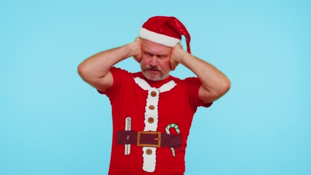 Человек в рождественской футболке закрывает уши и жестикулирует "нет", избегая советов, игнорируя неприятный шум — стоковое видео