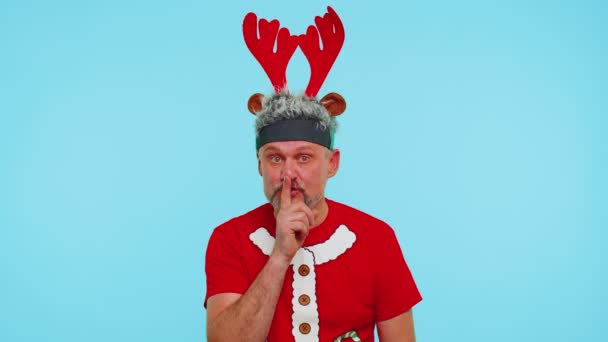 Man wears red Christmas t-shirt presses index finger to lips makes silence gesture sign, secret — Stock Video